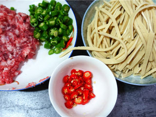 2、肉末烧豆腐皮,将猪肉剁成肉糜,青红椒洗净切细,豆腐皮切丝。姜蒜剁成末。