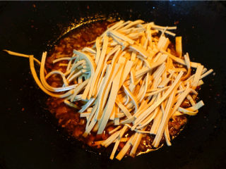 9、肉末烧豆腐皮,将豆腐皮丝放入锅里,大火烧开,转小火烧制,盖锅盖。