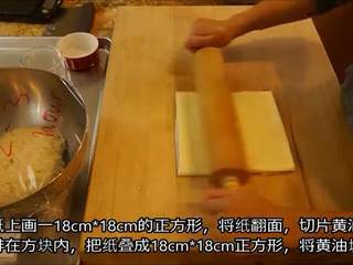 3、冬日完美安抚美食—可颂甜甜圈(完全手工版),在油纸上画18*18cm的正方形,将纸翻面,切片黄油整齐排在方块内,把纸叠成18*18cm正方形,将黄油块擀匀