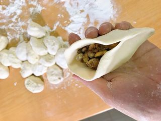 15、红糖伍仁馅糖三角,对折，一头捏起，捏到接近中间。开口部分，向中间推，捏住。