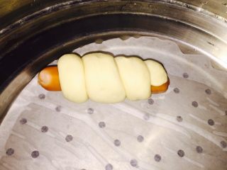 5、卷卷火腿肠,拿出一根火腿，把面团一圈圈的围住.