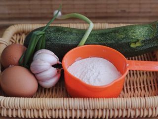 1、记忆中的角瓜鸡蛋饼,首先把角瓜用自来水冲洗干净，把小香葱去皮后用清水冲洗干净，准备好两个鸡蛋，还有1头山东紫皮大蒜；