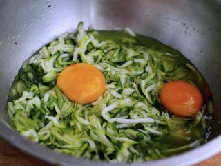 5、记忆中的角瓜鸡蛋饼,这个时候把两个鸡蛋打入腌制好的角瓜丝盆里，用手动打蛋器把角瓜丝搅拌均匀后；