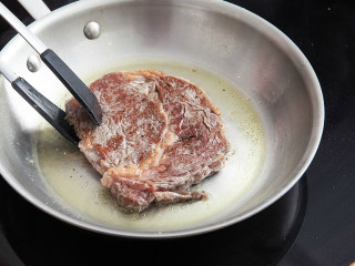 6、橄榄油煎牛排,煎1分钟后翻面煎40秒钟出锅，随即放在木板上静置1分30秒钟