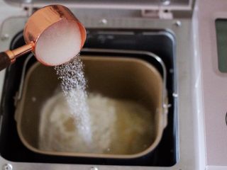 2、圣诞雪花豆沙包,把称重后的高筋面粉和低筋面粉先放入面包桶里，再放入盐和奶粉，花生油和清水，再把全蛋液和甘汁园双碳白砂糖和2克酵母，这个白糖听说是无硫的比较健康，而且不容易变色，特别好溶解。