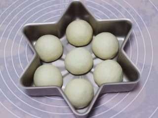 8、圣诞雪花豆沙包,每一个面团都如此重复步骤，包好的面团收口向下，放入提前抹油了的雪花型模具中摆好。