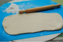 6、可颂,用擀面杖将面团擀成长方形的大片。