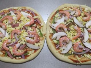 15、鲜虾火腿披萨,食材和芝士碎交错这撒在饼皮上，最后摆上剥壳的虾仁。