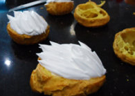 15、天鹅泡芙,烤好的空心泡芙均匀切开,分割成两层,下层挤上羽毛状的奶油,上层剪出两个翅膀的形状。最后将烤好的脖子插入奶油,翅膀呈飞翔状态插在奶油两边,装饰就完成啦。