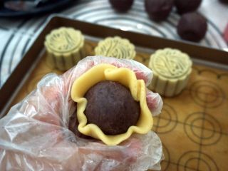13、50克广式红豆蓉月饼,面皮压薄后，将馅料包裹好。
