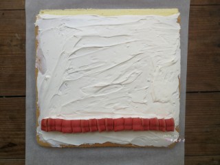 24、彩绘玫瑰蛋糕卷,将晾凉的蛋糕片放在干净的油纸上，没有彩绘玫瑰的那面朝上，四周切平整，底端45度斜切，然后抹上打发的淡奶油，铺上一排夹心用的心型红丝绒蛋糕，铺夹心的时候要挨着铺紧凑些，不能留有空隙