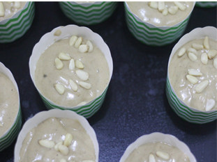 14、吃一次就会爱上的朴素小蛋糕——枣泥戚风小蛋糕,倒入小纸膜中，撒上松子仁