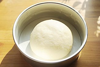 4、奶酪包,取出发酵好的面团，轻轻用手掌按压排气，然后再次整圆，放入抹了黄油的八寸圆模中；