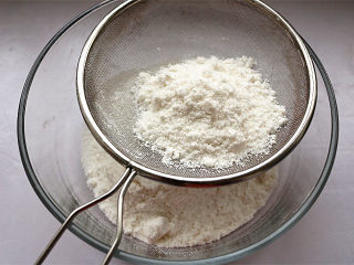 6、红豆蒸松糕,将搓散的面团过筛，可以借助小勺轻轻按压。过筛可以使米粉均匀，蒸出来的米糕才会松松软软。