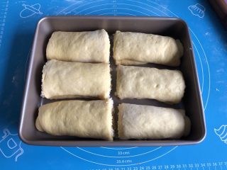 12、南瓜椰蓉面包,另一半面团同样操作，切好的六分面包坯摆入11寸烤盘，表面覆盖保鲜膜进行第二次发酵