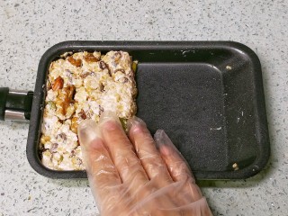 8、果仁燕麦能量棒,离火，由于FLUFF棉花糖本身就是液态，因此加热时间不长，温度不会太高，可以直接用手（戴手套）在锅里把果仁燕麦按紧整形，压成厚片，晾凉。