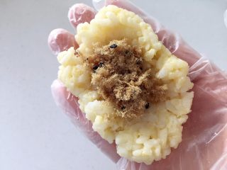 3、肉松小鸡饭团—带给宝宝更多有趣的童年回忆,把步骤3中的饭团均匀分成2份，取其中1份的2/3用手捏成椭圆小碗状，在中间放入一半的肉松。