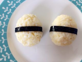 6、肉松小鸡饭团—带给宝宝更多有趣的童年回忆,取出海苔，用剪刀剪出两个长条，在中心位置把饭团卷起来