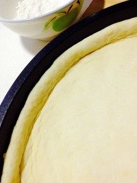 7、香蕉玉米披萨,披萨盘刷油、放入面皮,手向四周推动着、铺满、边缘呈高檐。