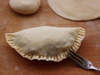 14、鲜掉眉毛的烟台韭菜盒子,把放入馅料的面皮用手把面皮的边边捏紧后，用叉子在面皮边边边上压一下，嫌麻烦的可以省略此步骤哈