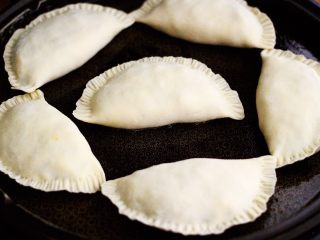 16、鲜掉眉毛的烟台韭菜盒子,电饼铛提前预热后，用硅胶勺子蘸少许食用油把电饼铛的锅底刷匀后，把包好的韭菜盒子放入锅中；