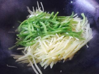 10、#圆土豆# 花椒油青椒土豆丝,土豆丝炒至九成熟时放入青椒丝，翻炒均匀。