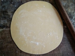 7、手擀面,在面饼表面撒些薄面，用擀面杖慢慢擀开。