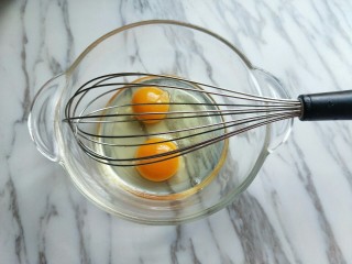 2、#做妈妈的拿手菜#可可颗粒蛋仔,将鸡蛋放入大口玻璃器具中，用手动打蛋器打散。