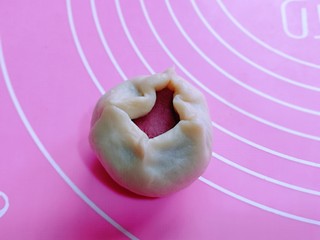 8、中式甜点~蜜豆桃花酥,取一个油皮按扁,擀圆,包入一个油酥。虎口手法包起来,收口捏紧朝下。