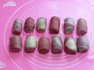 13、中式甜点~蜜豆桃花酥,松弛好的面团,再次按扁,再一次用擀面杖擀成长牛舌状,再一次卷起,盖上保鲜膜,再次松弛15分钟。