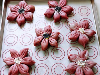 19、中式甜点~蜜豆桃花酥,依次做好所有的桃花的形状,放在垫油纸的烤盘中,再每个桃花酥中间抹上蛋液。再撒上给白芝麻,如图。