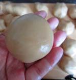 14、京式提浆五仁月饼,右手按住馅料，左手慢慢将饼皮推匀，包好