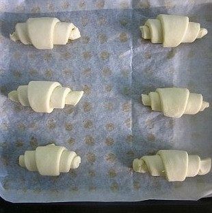 10、可颂,将切好的三角形从底边开始卷起来,卷成牛角形,再一个个整齐的排放在烤盘中,放进发酵箱36度进行最后发酵。