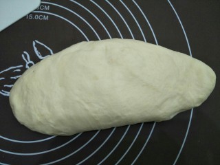 10、炼奶小馒头(烤箱版),拿出面团在案板上压扁，来回揉一会进行排气，再揉圆。