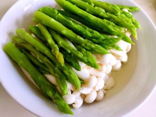 14、绿色美食+葱油芦笋白玉菇,将白玉菇用筷子再理整齐，将芦笋尖摆放上去，这时，碗内会有很多汤汁渗出