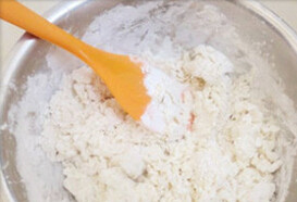 1、手撕芝麻葱油饼,煮滚后的开水绕圈圈般的倒入面粉中、用刮刀不停的搅拌, 呈松散的面团状即可