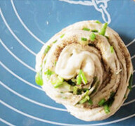 9、手撕芝麻葱油饼,将两份面一起卷成圆形饼胚，最后的尾巴收在饼下