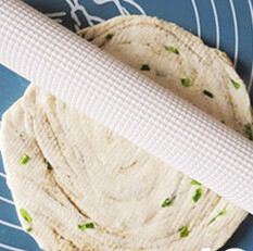 10、手撕芝麻葱油饼,盘好的面团松弛1小时后先将面团稍微压平，后用擀面杖轻轻擀开