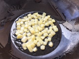 5、土豆腊肉焖饭,土豆切好后防止氧化，马上放锅里用油炸干，当然啦！炸土豆丁目的是为了等一下焖煮时不会煮散烂，炸过的土豆口感更佳。