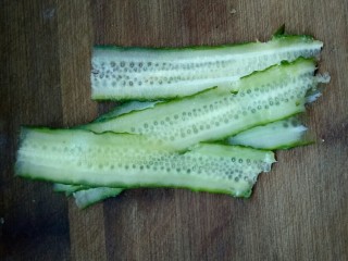 2、创意菠萝饭,黄瓜用刮皮刀刮成薄片,再对半切开。