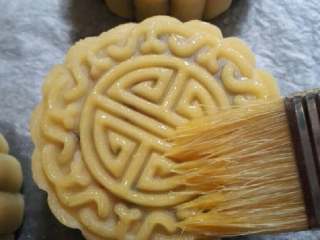 16、五仁月饼,喷一点点水，放入预热好烤箱中，（温度170℃，烤15—20分钟），烤5分钟后，取出凉5分钟刷适量蛋液，再继续烤。