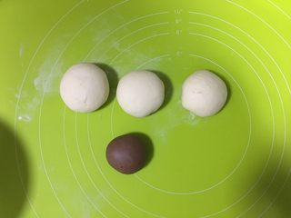 5、呆萌熊猫豆沙包,把面团分为3大一小的面团，小的那份加入可可粉，加一汤匙水揉匀，其他三份等大