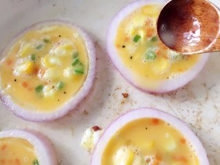 9、洋葱圈煎蛋饼-可以和宝贝抢着吃的美食,用勺子将鸡蛋液舀入洋葱圈内，注意不要放太满，齐平或九分满即可，煎的过程中鸡蛋液会稍稍膨胀，太满溢出影响最终成品颜值哈。