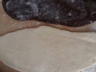 3、????猫耳朵????,取出面团,把红白两色两色面粉擀成薄片,白色的稍微大点的,把红色面团放在白色上面卷起来