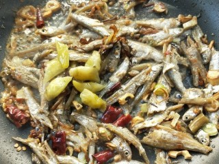 18、和和美美酸爽芋荷炒鱼干,倒入改刀的野山椒和野山椒水，翻炒，让鱼干吸收辣味。