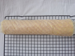 8、草莓卷,借助油纸和擀面杖把蛋糕片卷成圆柱状,用油纸包好放入冰箱冷藏定型