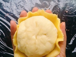 14、菠萝面包,把压成薄饼状的菠萝皮轻轻移到手掌心，放入包了菠萝馅的面团、把边边的菠萝皮往面团里收一收即可