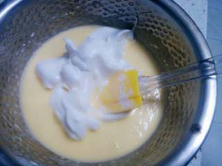 3、酸奶蛋糕,将三分之一的打发蛋白加入调好的蛋糊盆中,上下翻动均匀混合。