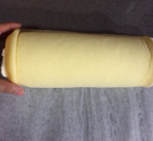 16、日式棉花蛋糕卷,将起始端油纸提起，将蛋糕片轻轻压下，徒手将蛋糕片轻轻卷起后，用油纸裹好，冷藏定型