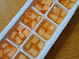 5、蜜瓜遇上冰,把刚才的哈蜜瓜丁分别放入冰格，加入蜂蜜水，放进冰箱冷冻一夜